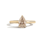Gold ring with a pear-shaped diamond on a white background