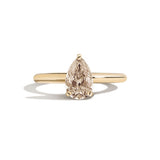 Gold ring with a pear-shaped diamond on a white background