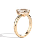 Gold ring with a pear-shaped diamond on a white background
