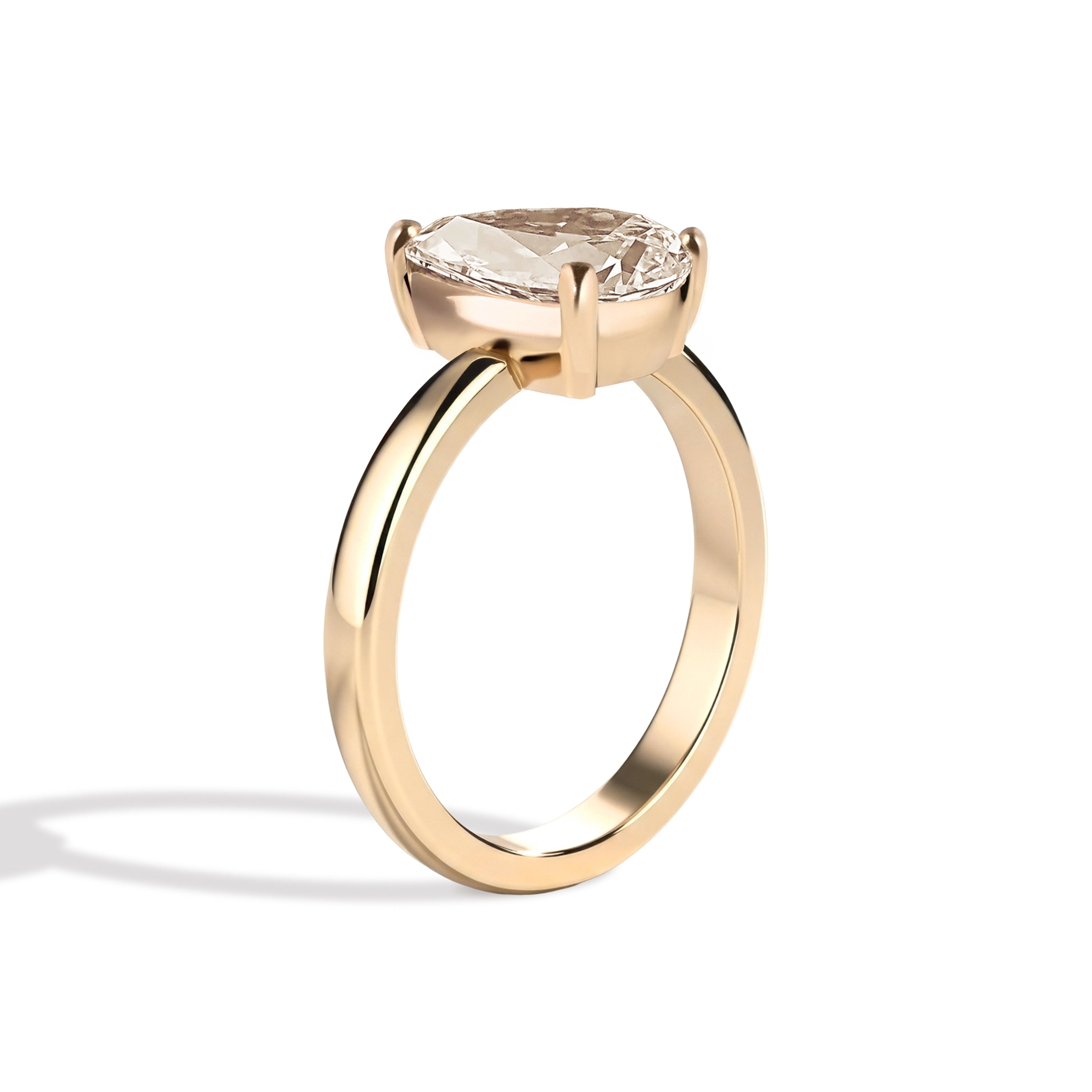Gold ring with a pear-shaped diamond on a white background
