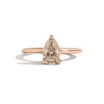 Rose gold ring with a pear-shaped diamond on a white background