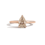 Rose gold ring with a pear-shaped diamond on a white background
