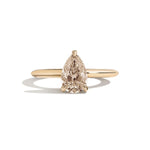 Gold ring with a pear-shaped diamond on a white background