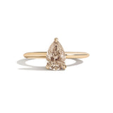 Gold ring with a pear-shaped diamond on a white background