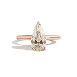 Gold ring with a pear-shaped diamond on a white background