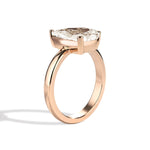 Gold ring with a pear-shaped diamond on a white background
