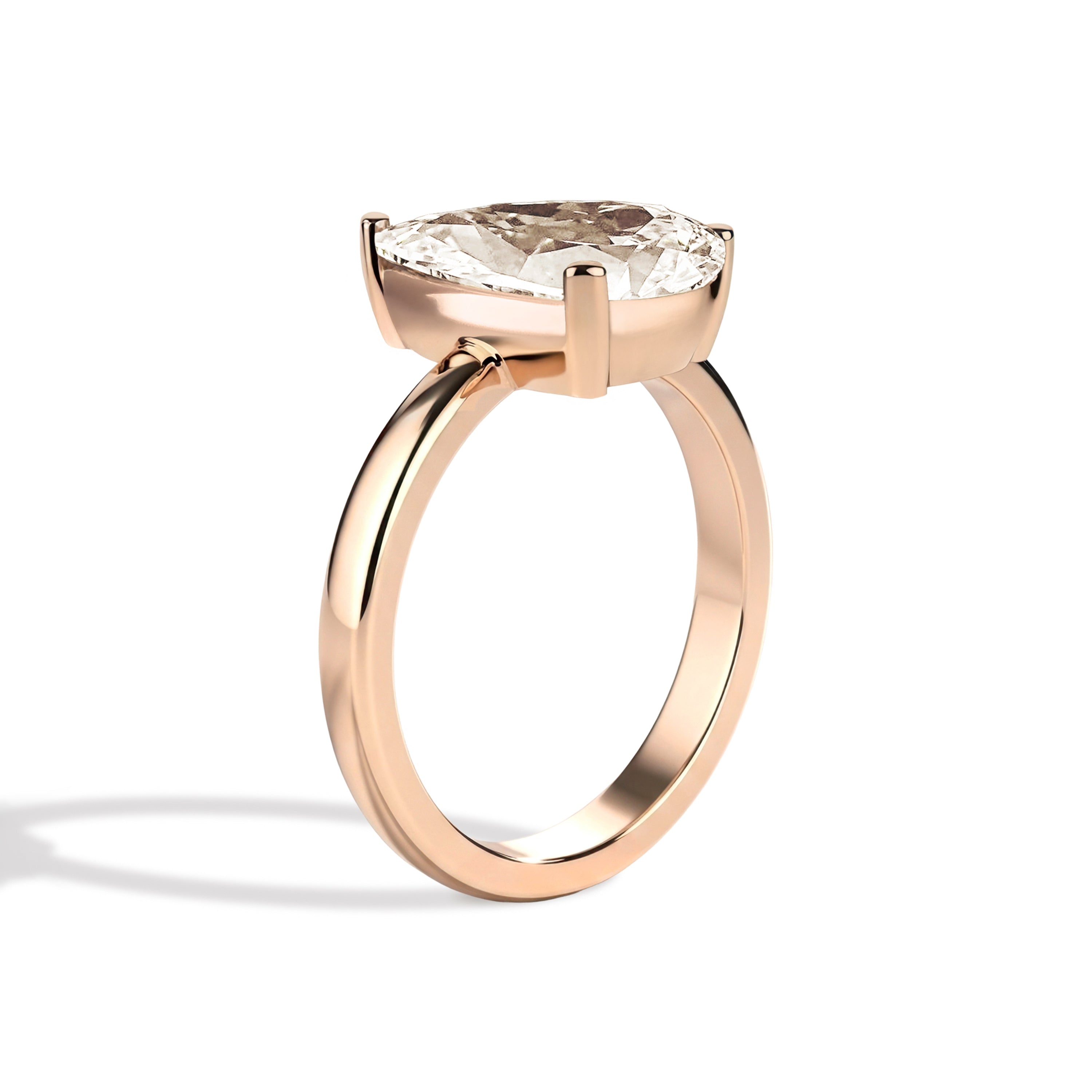 Gold ring with a pear-shaped diamond on a white background