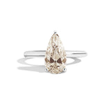 Gold ring with a pear-shaped diamond on a white background
