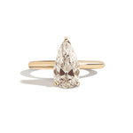 Gold ring with a pear-shaped diamond on a white background