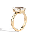 Gold ring with a pear-shaped diamond on a white background