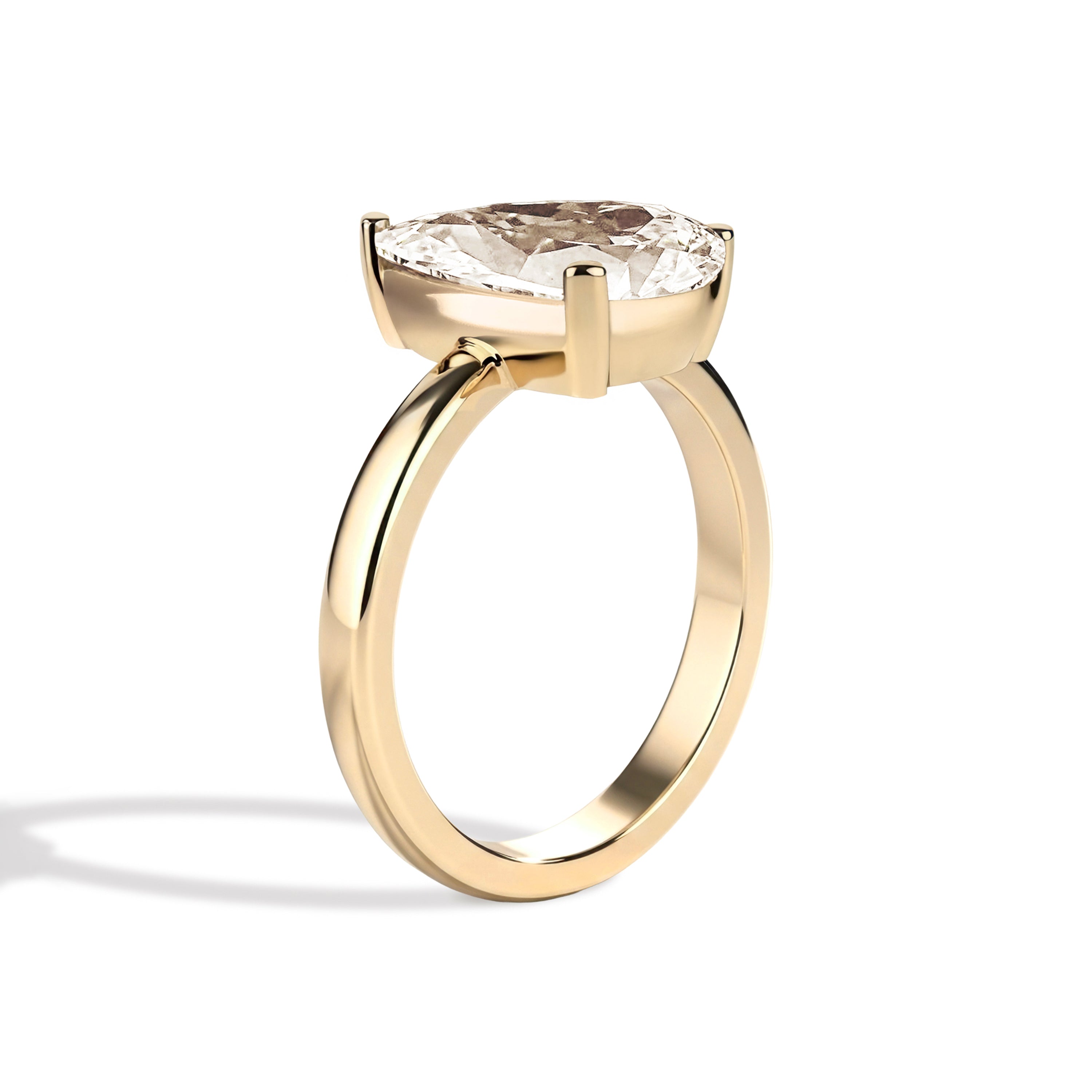 Gold ring with a pear-shaped diamond on a white background