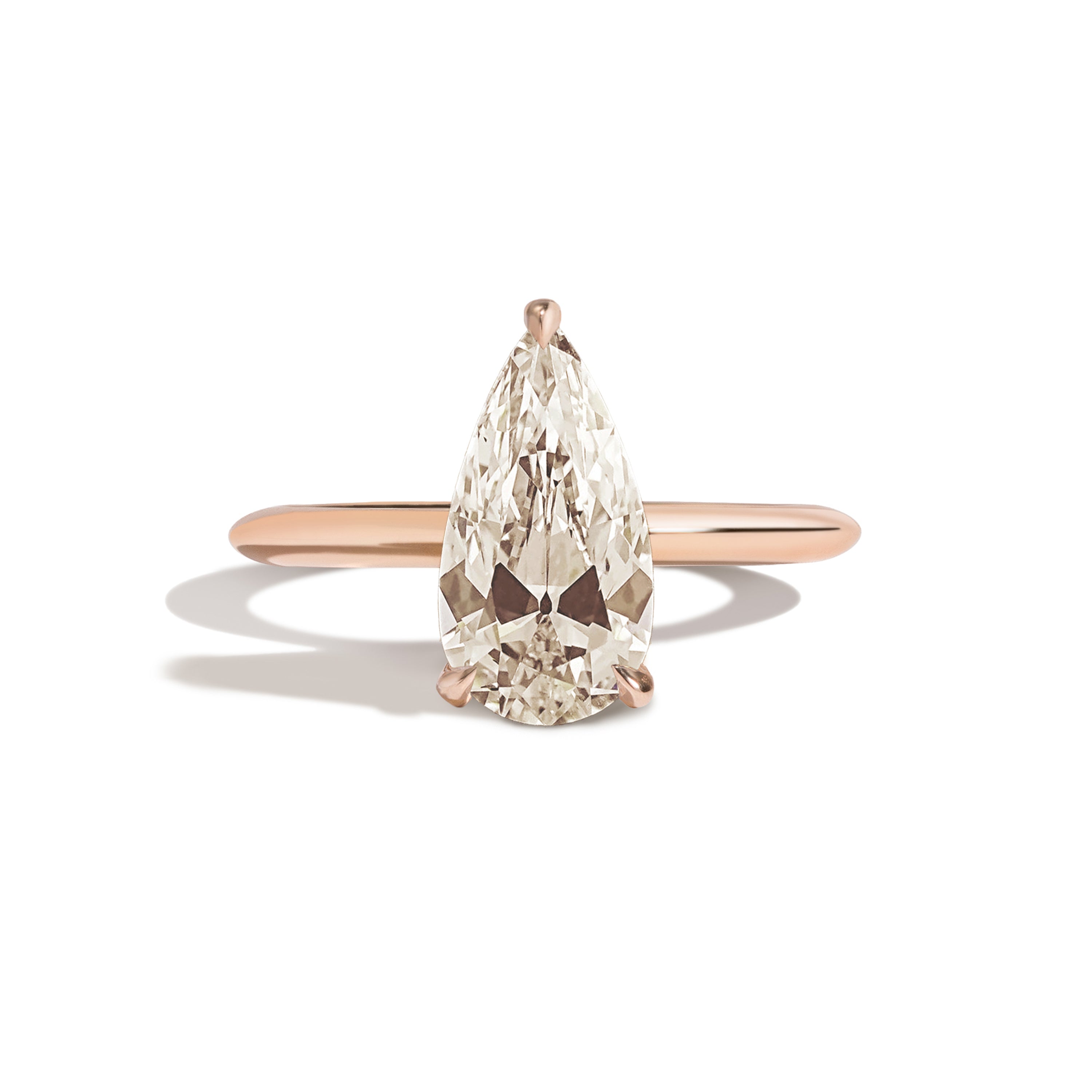Gold ring with a pear-shaped diamond on a white background