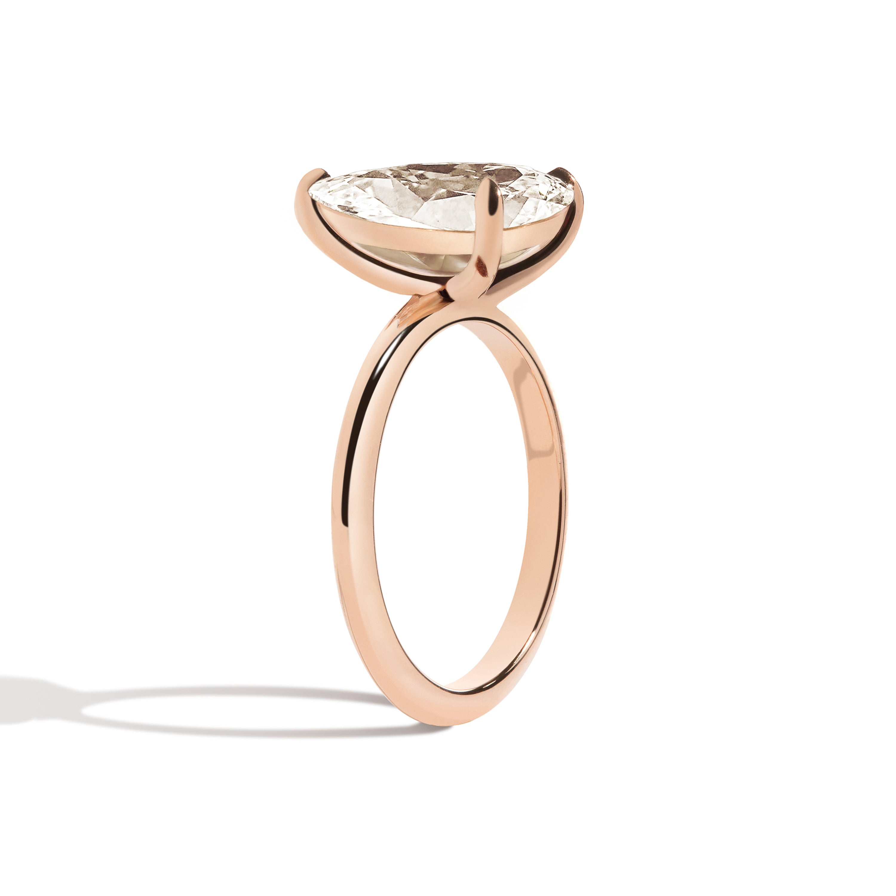 Gold ring with a pear-shaped diamond on a white background
