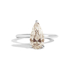 Gold ring with a pear-shaped diamond on a white background