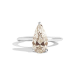 Gold ring with a pear-shaped diamond on a white background