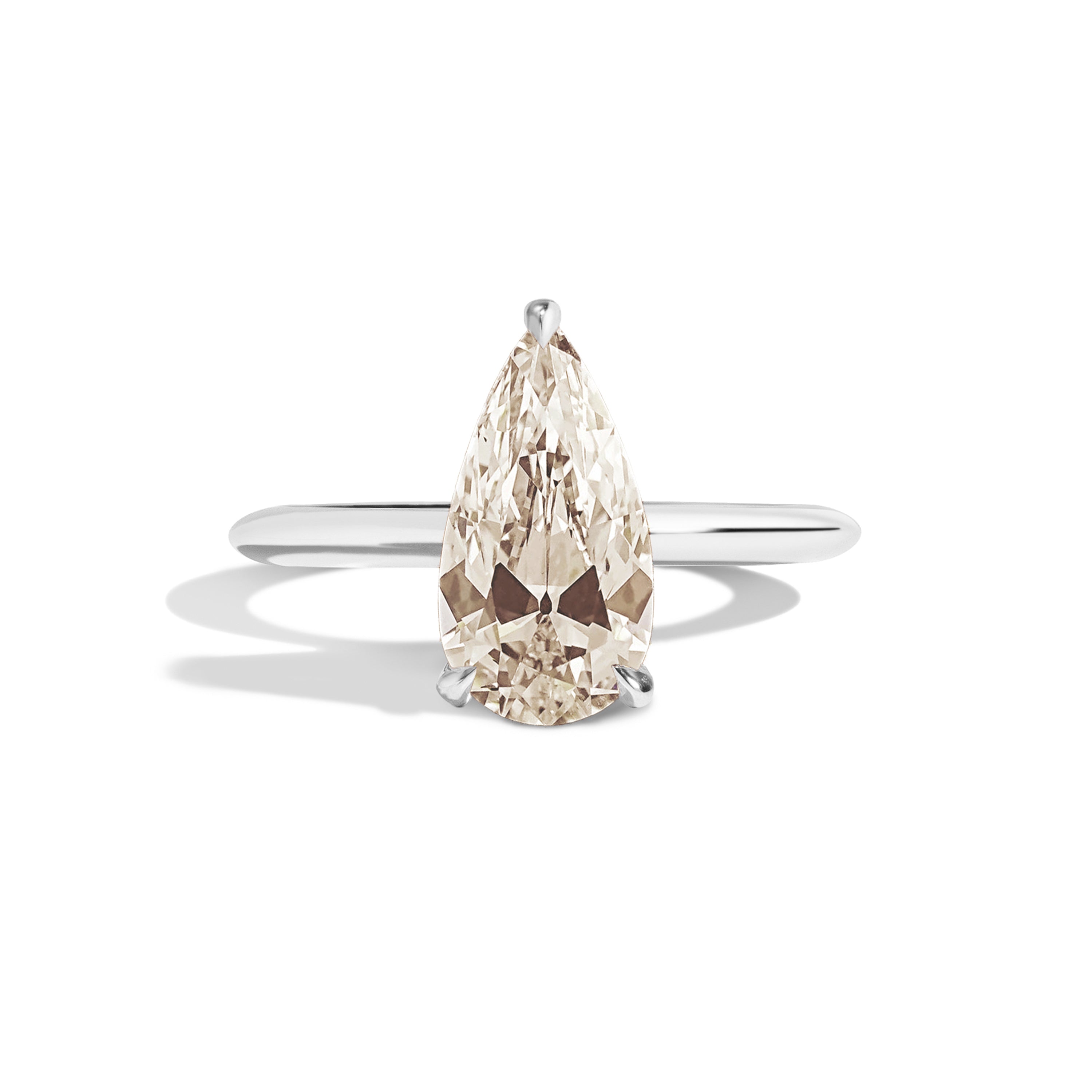 Gold ring with a pear-shaped diamond on a white background