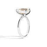 Gold ring with a pear-shaped diamond on a white background