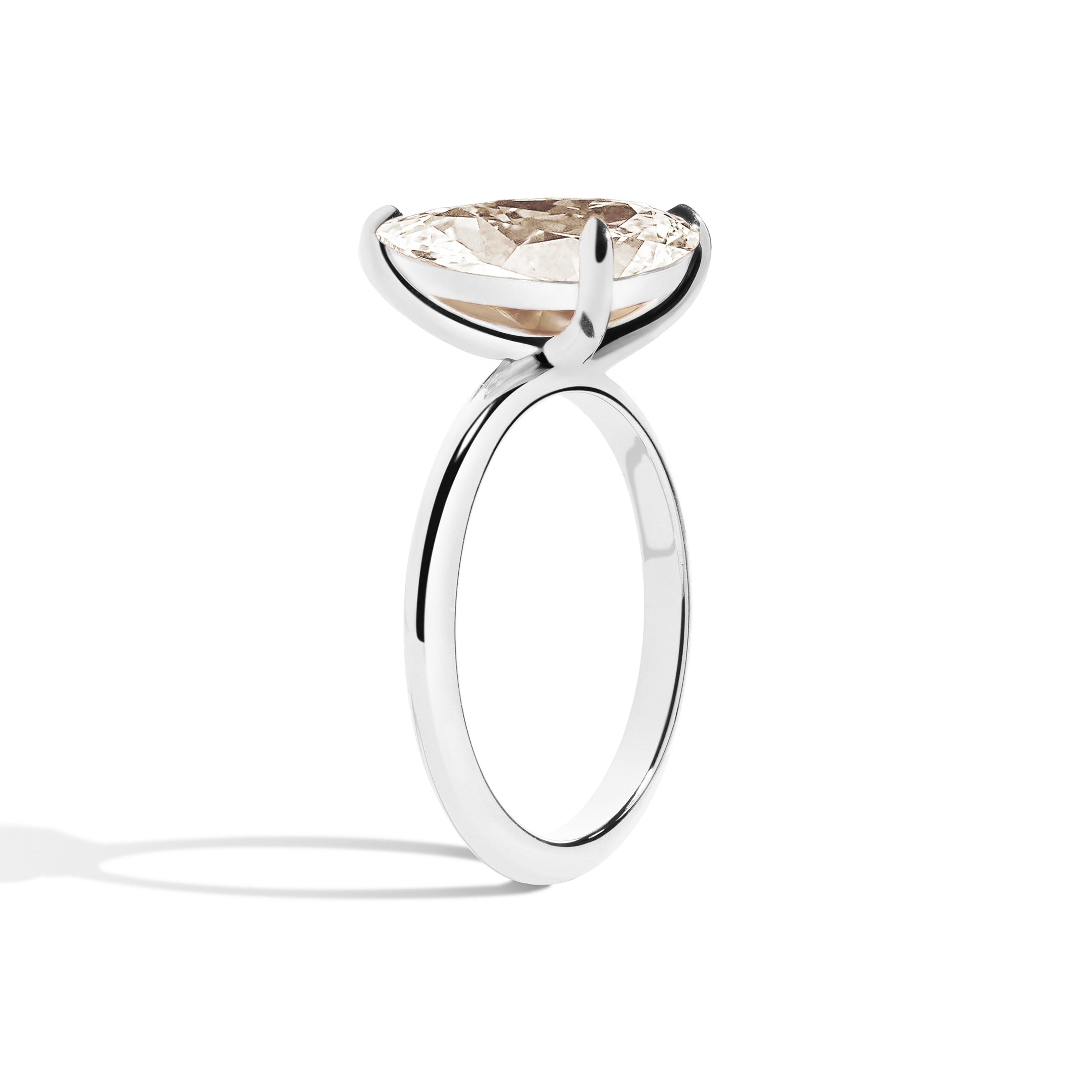 Gold ring with a pear-shaped diamond on a white background