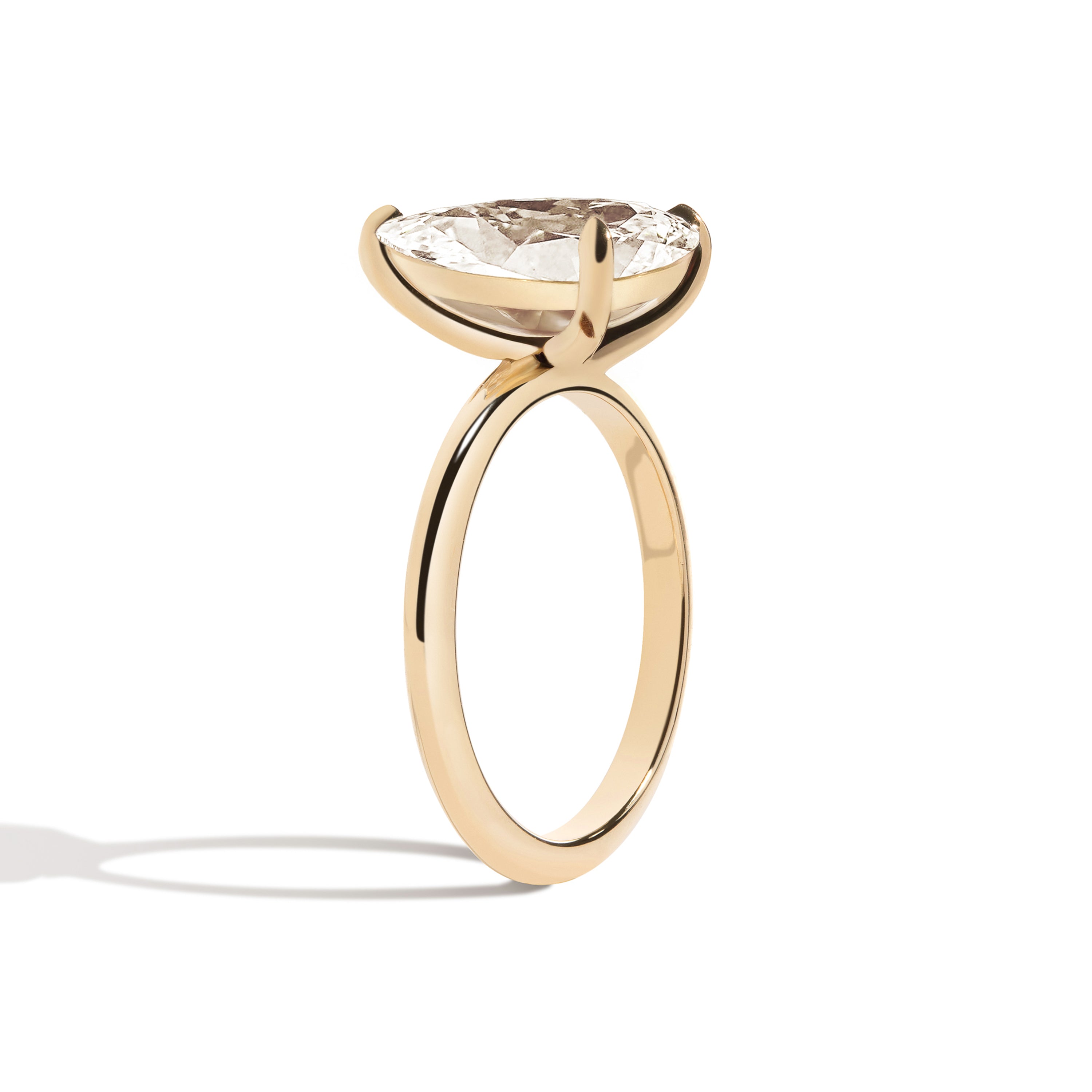 Gold ring with a pear-shaped diamond on a white background
