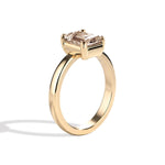 gold ring with a champagne emerald-cut diamond on a white background
