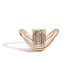 A yellow gold ring featuring an emerald-cut diamond center stone, set against a clean white background with a soft shadow.