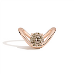 A rose gold ring with a curved, open curved shaped band and a round-cut diamond center stone, shown on a clean white background with a soft shadow.