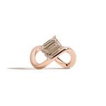 A rose gold infinity-shaped ring featuring a tilted emerald-cut champagne diamond center stone, set against a clean white background with a soft shadow.