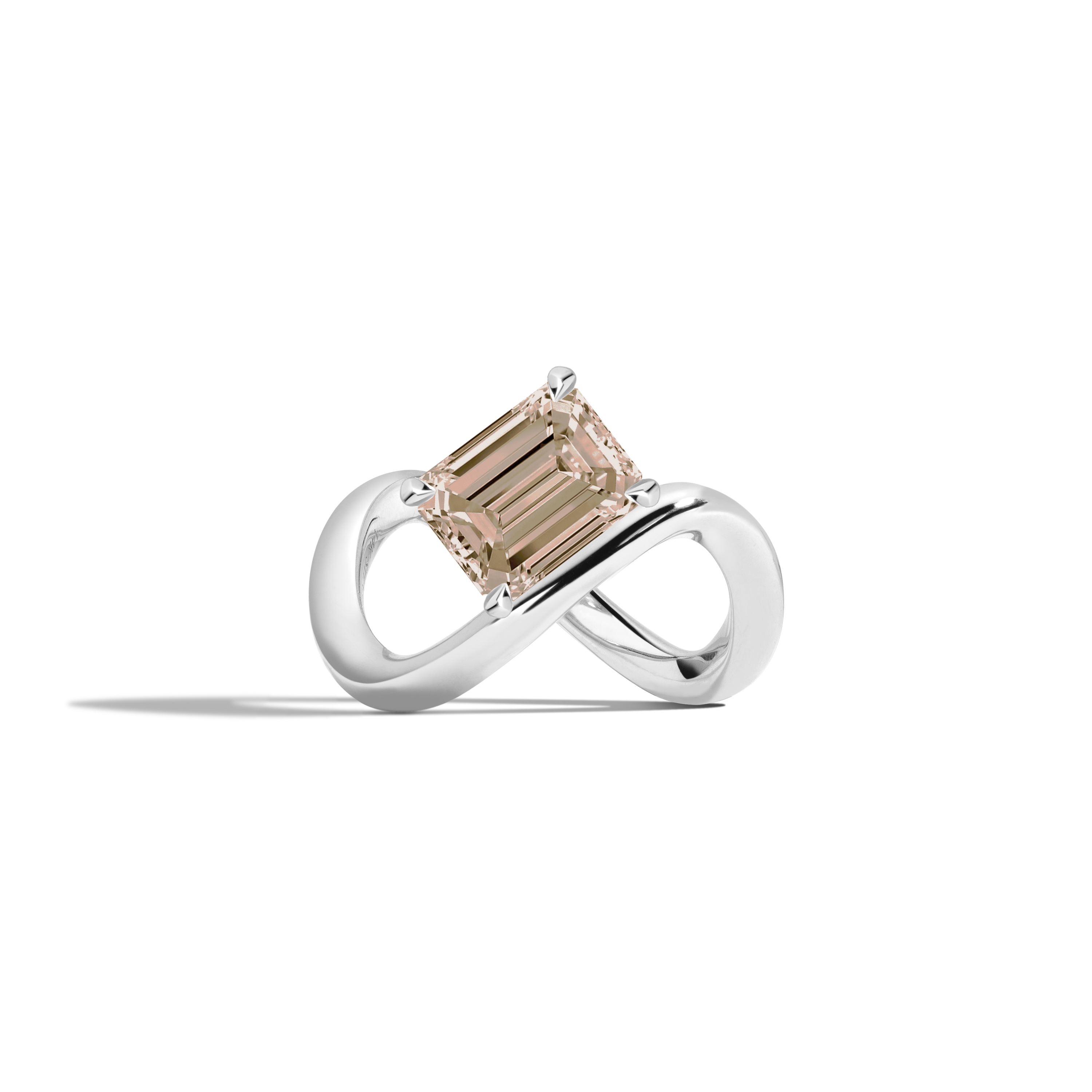 A white gold infinity-shaped ring featuring a tilted emerald-cut champagne diamond center stone, set against a clean white background with a soft shadow.