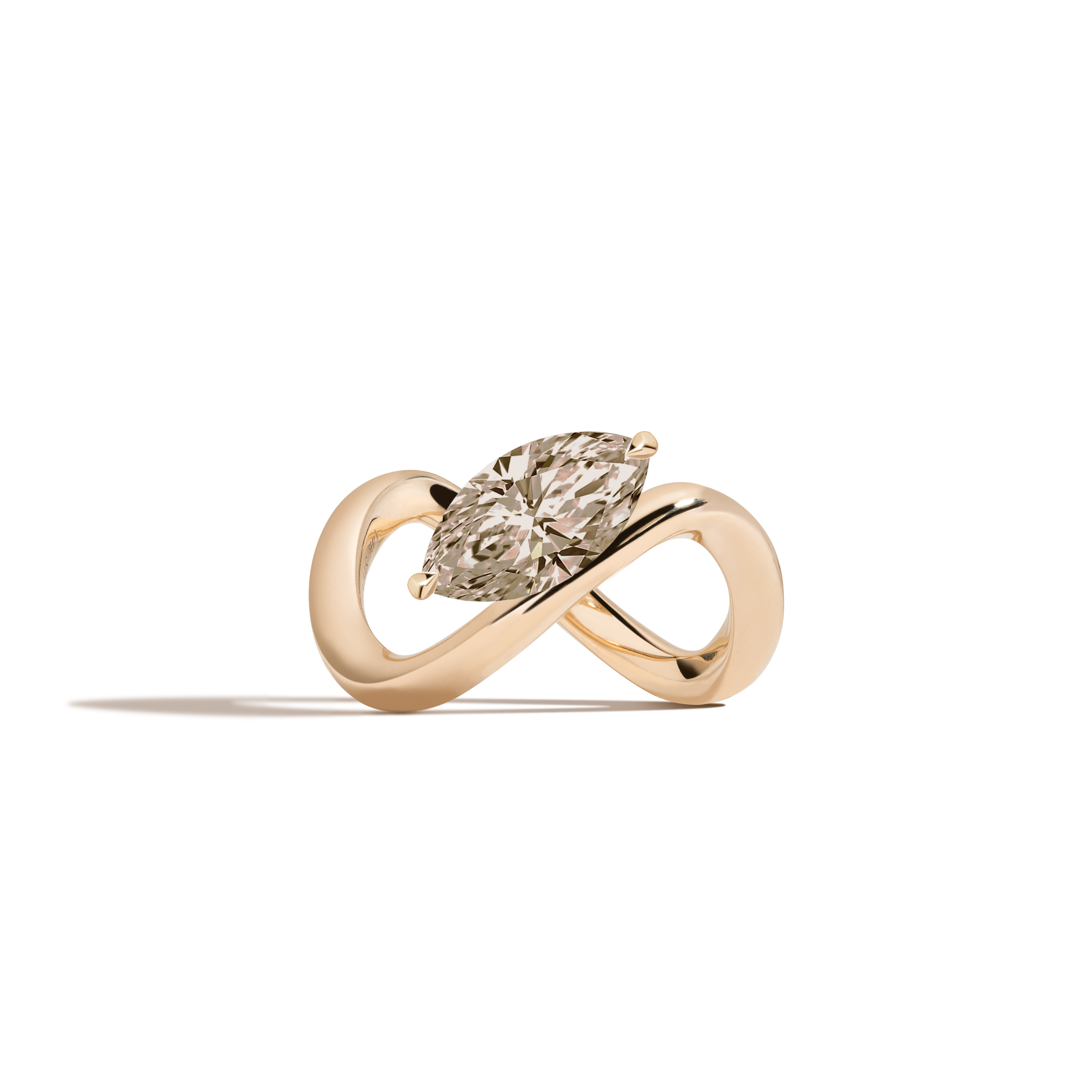 A yellow gold infinity-shaped ring featuring a tilted marquise champagne diamond center stone, set against a clean white background with a soft shadow.