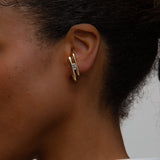 An ear with a yellow gold earring with a diamond