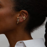 An ear with two yellow gold earrings with diamonds