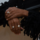 Hands wearing three yellow and white gold rings with diamonds