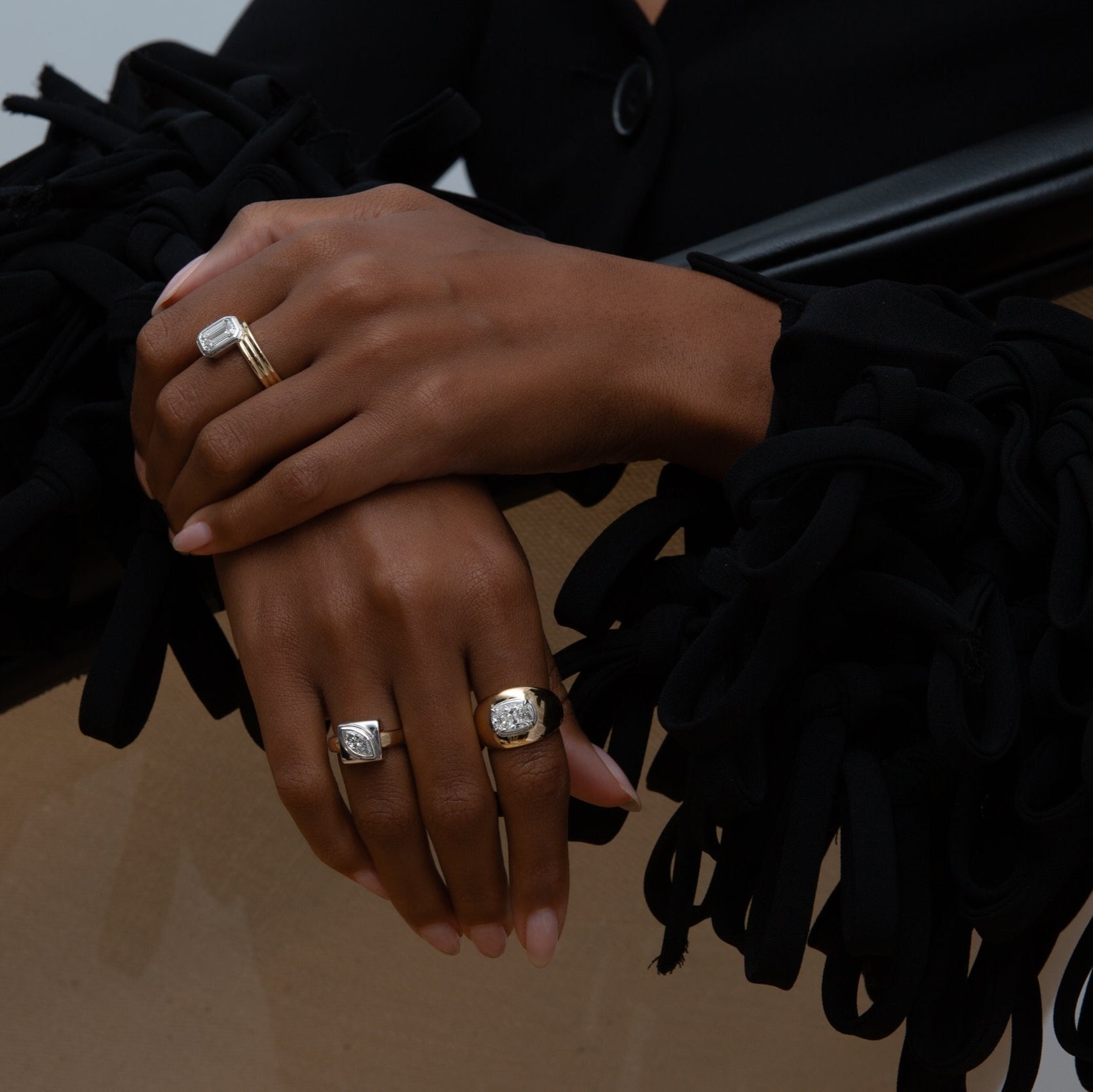 Hands wearing three yellow and white gold rings with diamonds