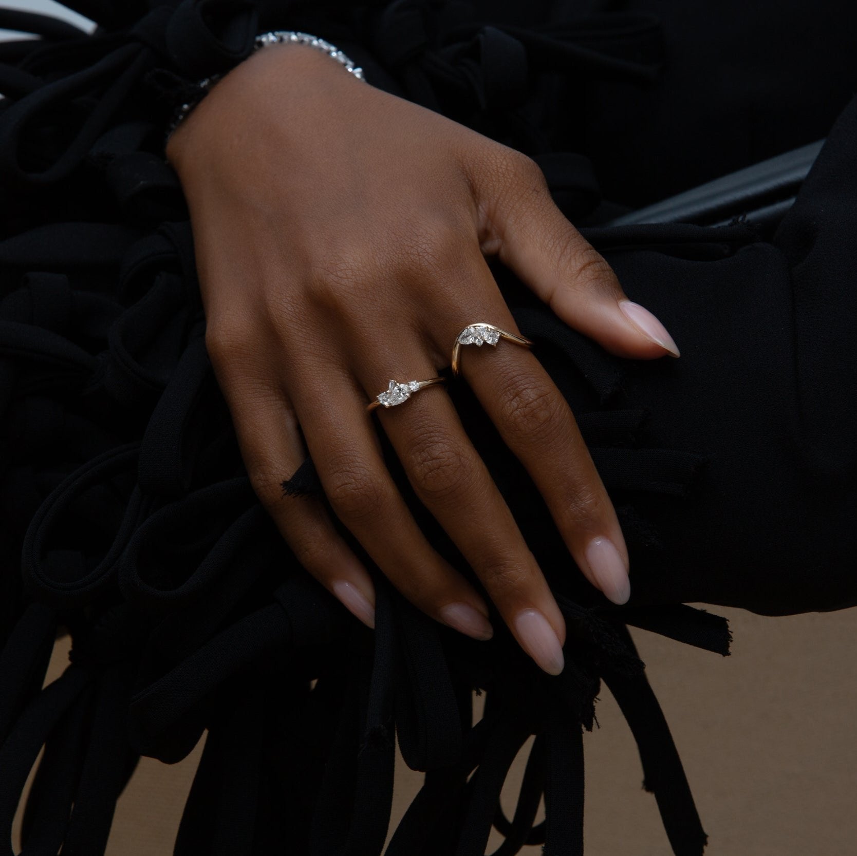 A hand wearing two yellow gold rings with diamonds