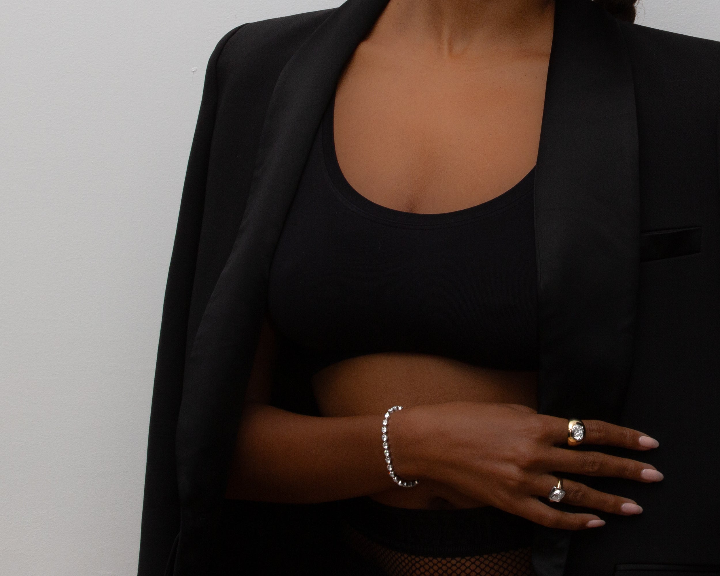 Person wearing a black outfit with jewelry on a plain background