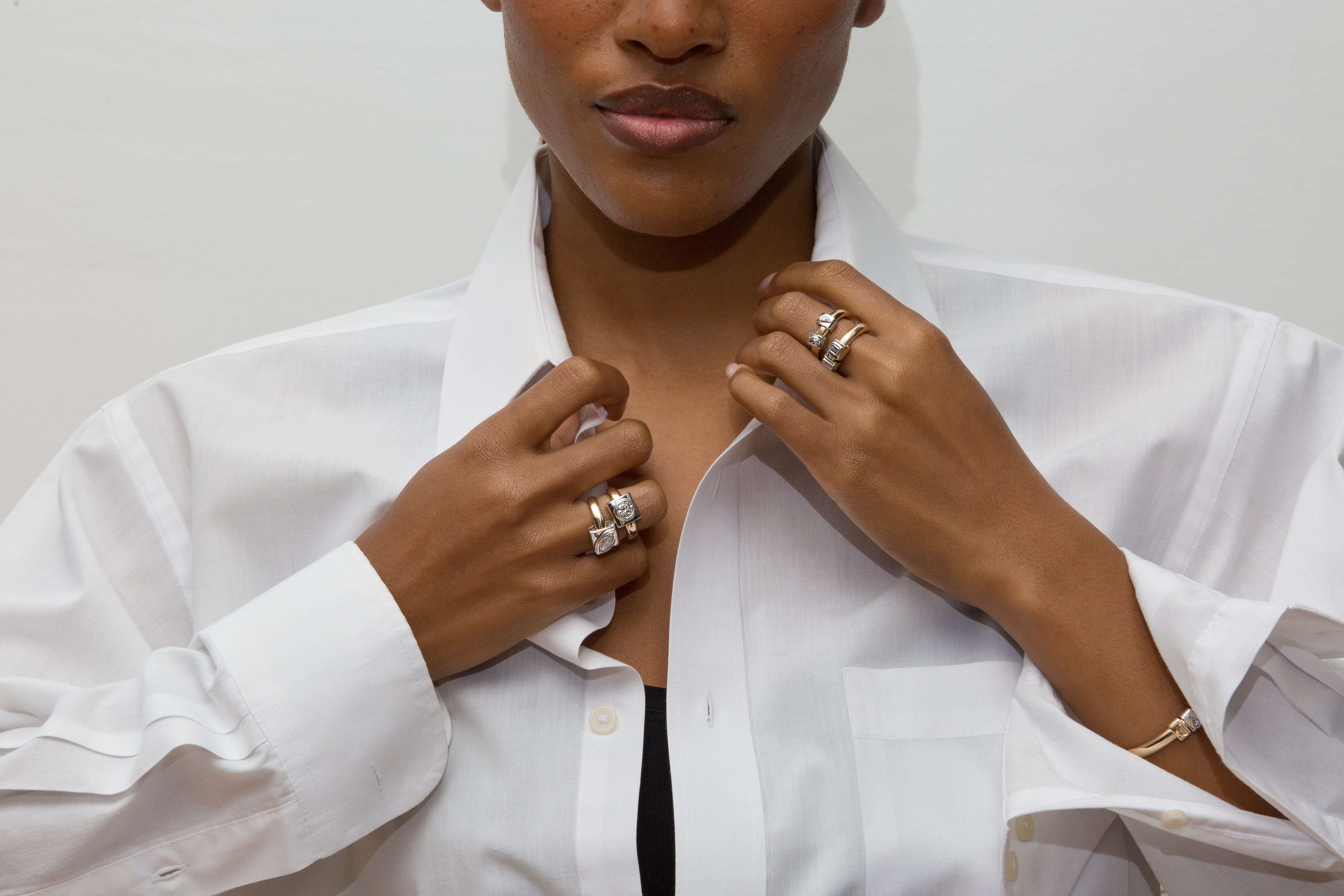 Person wearing a white shirt with visible jewelry on a plain background
