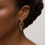 Close-up person wearing yellow gold earrings with two diamonds