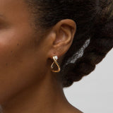 Close-up person wearing yellow gold earrings with pear diamond