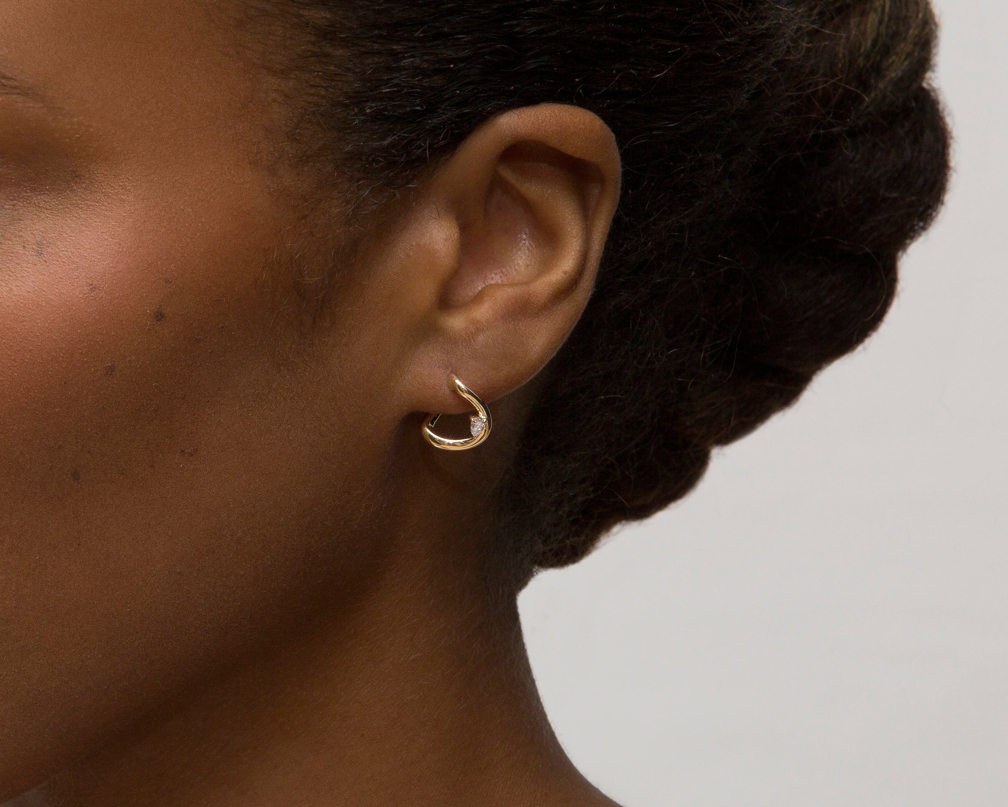 Woman with styled hair and earring on a plain background