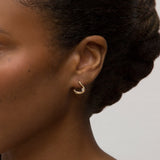 Close-up person wearing yellow gold hoop earrings with pear diamond