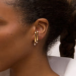 Person wearing 14k yellow gold earrings with diamonds