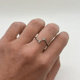 Hand wearing a silver ring with 2 diamonds on a light background