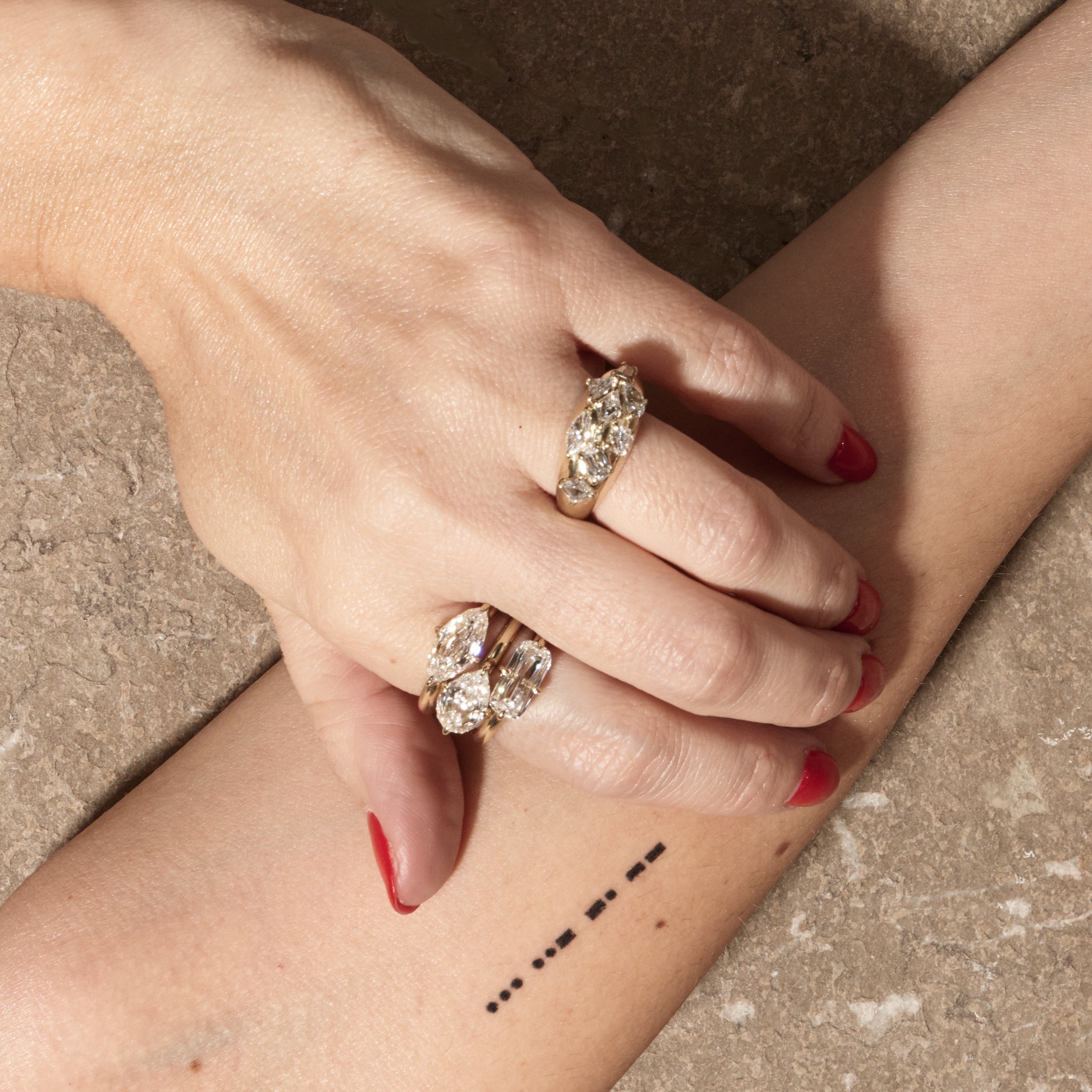 stacked engagement rings on hand with textured background