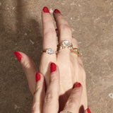 stacked engagement rings on hand with textured background