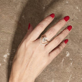  Oval railless engagement ring paired with curved pavé diamond band on hand with textured background