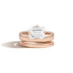 Rose gold ring with emerald-cut diamond on a white background