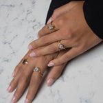gold rings on model's hand with white and gray background