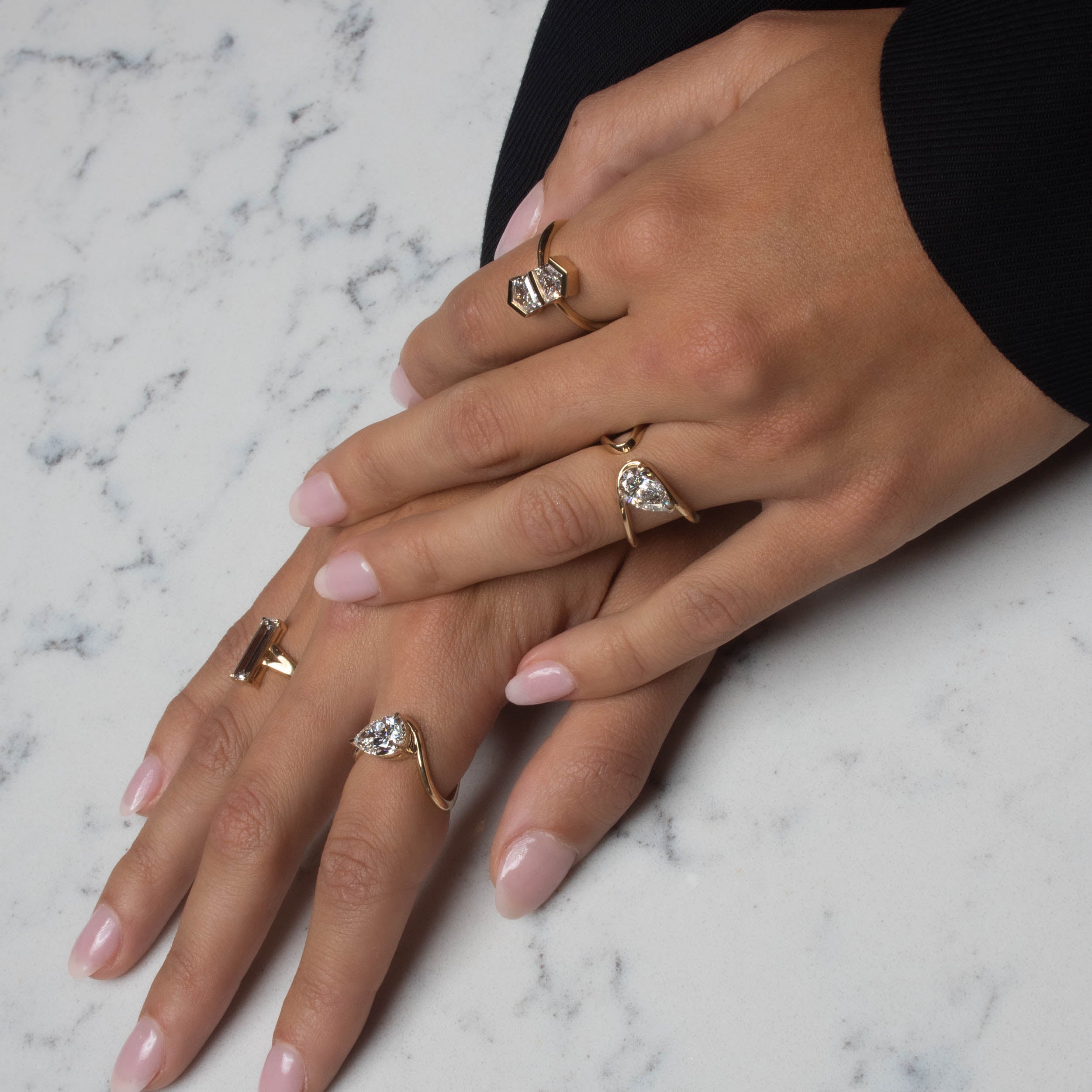 gold rings on model's hand with white and gray background