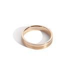 A gold-colored band ring with a polished finish and a grooved design at the center.