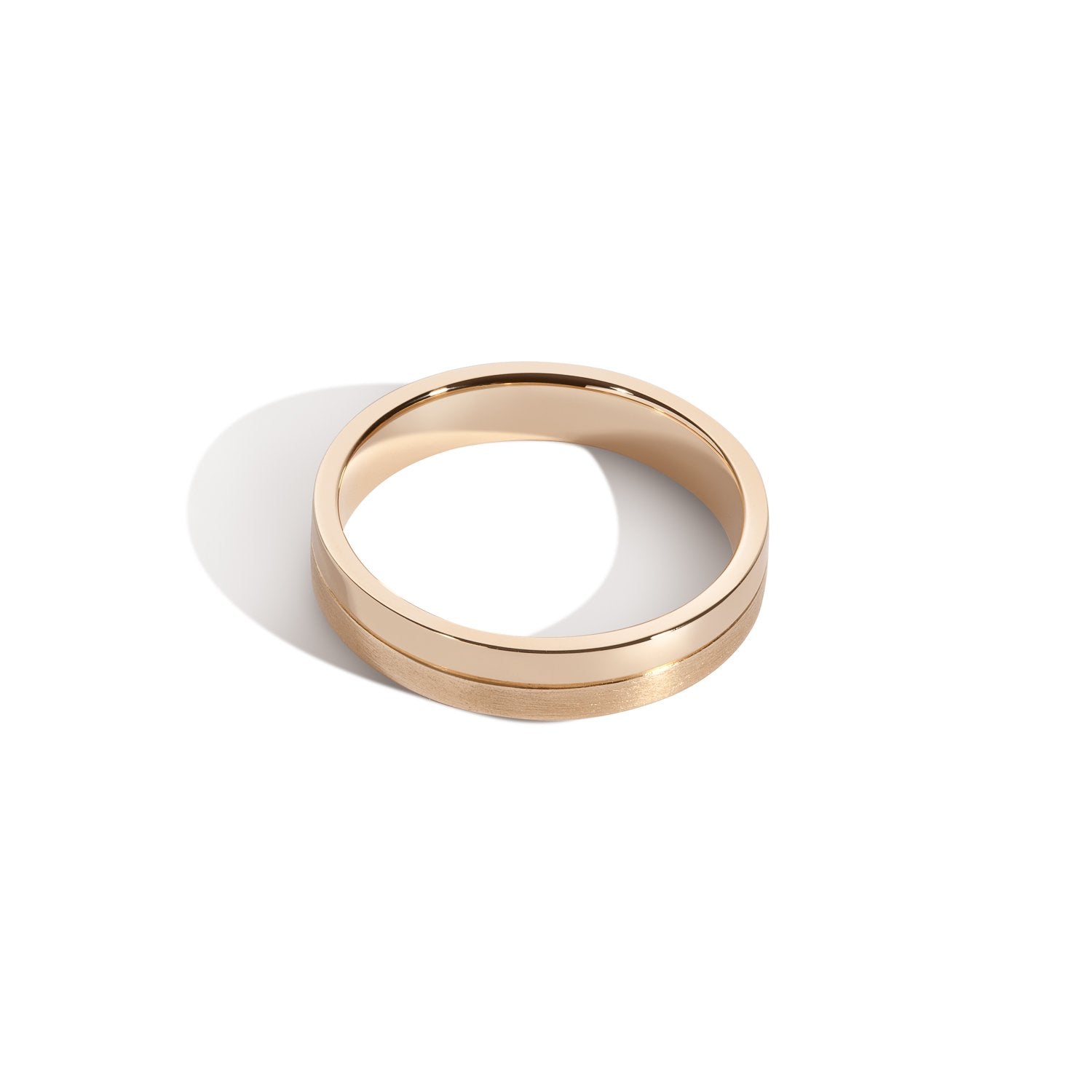 A gold-colored band ring with a polished finish and a grooved design at the center.